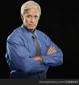 Caucasian middle aged businessman looking at viewer with arms crossed.