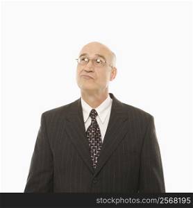 Caucasian middle-aged businessman looking indecisive standing against white background.