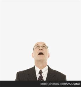 Caucasian middle-aged businessman looking up with mouth open against white background.