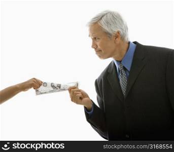 Caucasian middle aged businessman pulling one hundred dollar bill from woman.