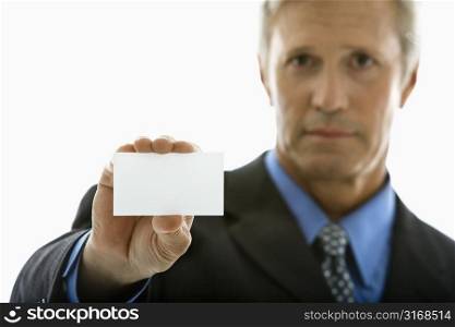 Caucasian middle aged man holding business card and looking at viewer.