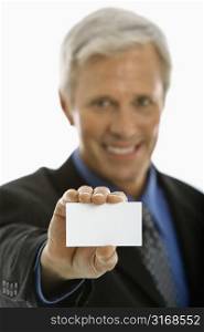 Caucasian middle aged man holding business card and smiling at viewer.