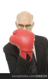 Caucasian middle-aged man holding up hand with red boxing glove up to face.