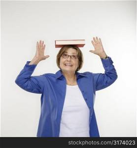 Caucasian middle aged woman balancing book on head.