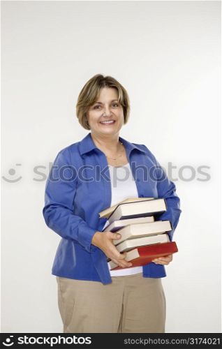 Caucasian middle aged woman holding stack of books.