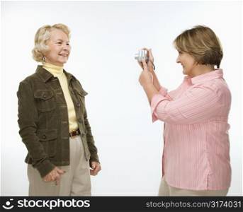 Caucasian middle aged woman taking photo with digital camera of senior woman.