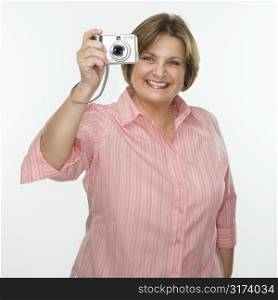Caucasian middle aged woman taking photo with digital camera of viewer.