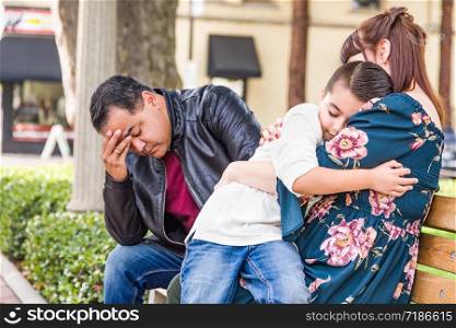 Caucasian Mother and Hispanic Father Comforting Mixed Race Son Outdoors.