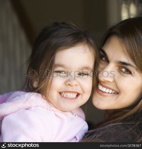 Caucasian mother holding daughter and smiling.