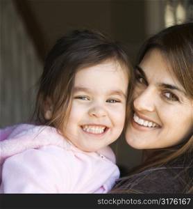Caucasian mother holding daughter and smiling.