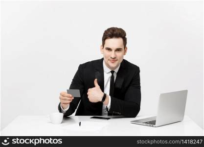 Caucasian office man in formal suit and tie demonstrating digital money in plastic credit card and showing thumb up isolated over gray background. Caucasian office man in formal suit and tie demonstrating digital money in plastic credit card and showing thumb up isolated over gray background.