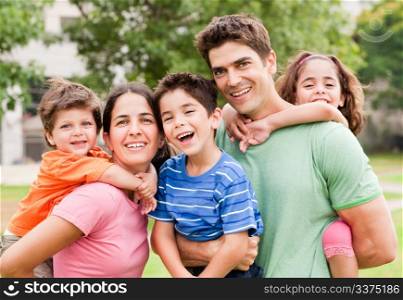 Caucasian parents piggyback their children, posing outdoors