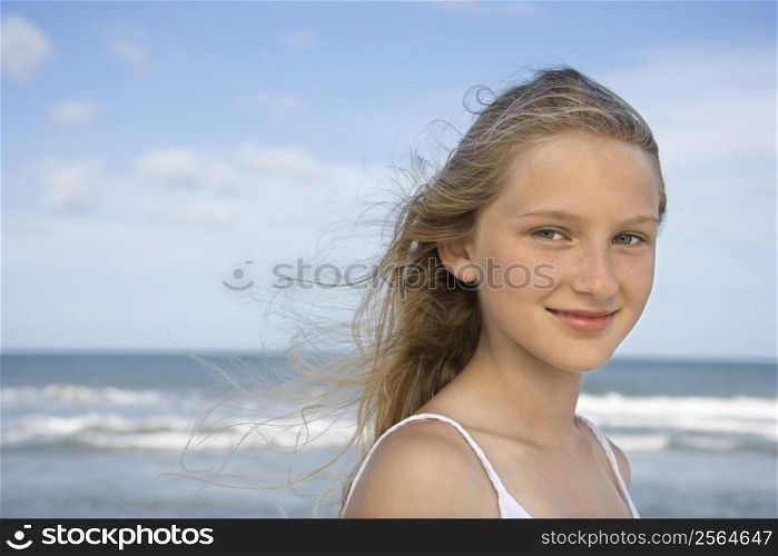 Caucasian pre-teen girl on beach looking at viewer.
