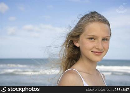 Caucasian pre-teen girl on beach looking at viewer.