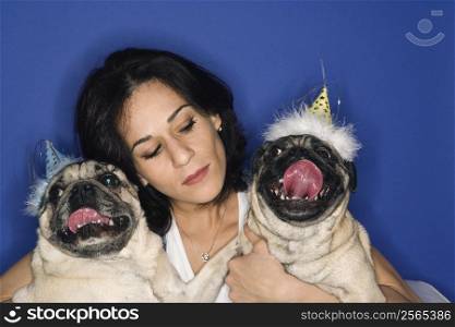 Caucasian prime adult female holding two Pug dogs.