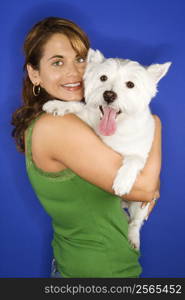 Caucasian prime adult female holding white terrier dog.