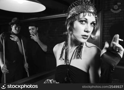 Caucasian prime adult female standing in front of pool table with two Caucasian prime adult men in background.