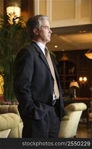 Caucasian prime adult male businessman standing in hotel lobby.