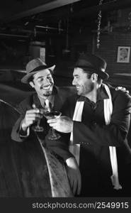 Caucasian prime adult retro males sitting at bar drinking.