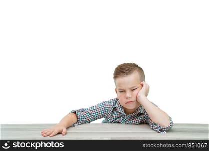 Caucasian school-age boy in a plaid shirt falls asleep sitting at the table