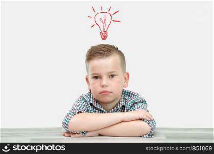 Caucasian school-age boy in a plaid shirt on an isolated background writes thoughts in a sheet.