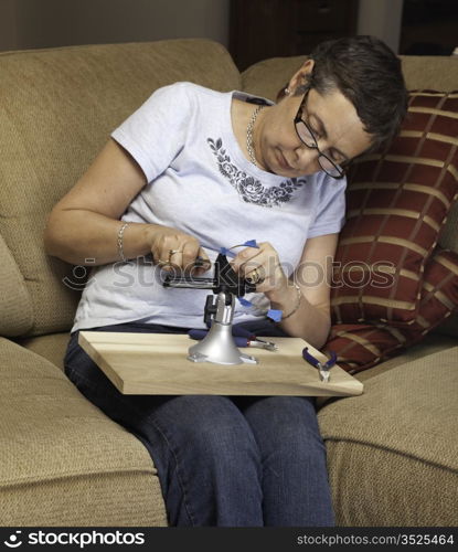 Caucasian senior lady starting to make a silver wire pendant in a vise or clamp