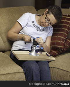 Caucasian senior lady starting to make a silver wire pendant in a vise or clamp