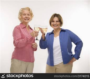 Caucasian senior woman and middle aged woman toasting wine glasses and smiling at viewer.