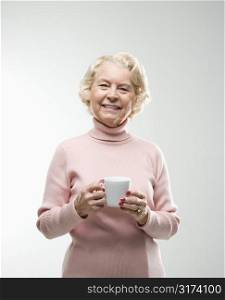 Caucasian senior woman holding coffee cup smiling at viewer.