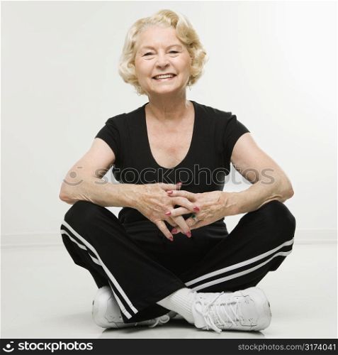 Caucasian senior woman sitting on floor with legs crossed.