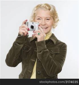 Caucasian senior woman taking photo with digital camera of viewer.