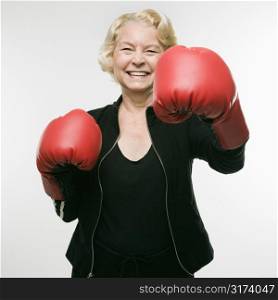 Caucasian senior woman wearing boxing gloves and throwing punch at viewer.