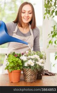 Caucasian smiling woman is pouring water in the plants