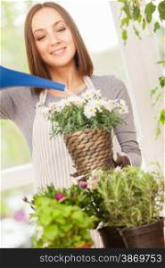 Caucasian smiling woman is pouring water in the plants
