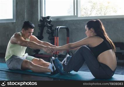 Caucasian sportive trainer is coaching beautiful woman to do exercise by doing sit up. Sport and Healthy Concept.