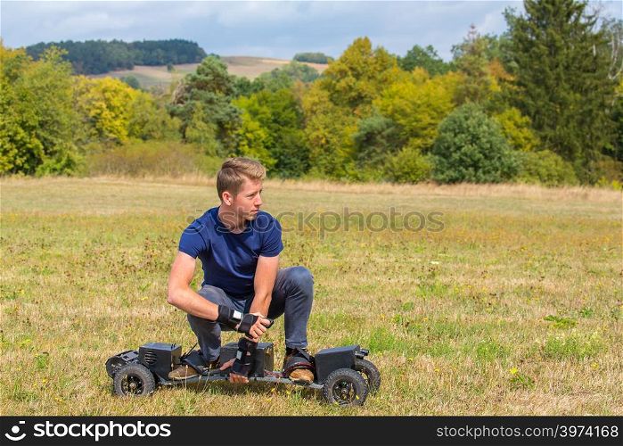 Caucasian teenage boy rides electrical mountainboard in grass field