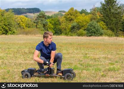 Caucasian teenage boy rides electrical mountainboard in grass field