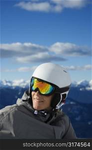 Caucasian teenage boy snowboarder wearing helmet and goggles on mountain.