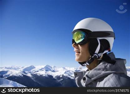 Caucasian teenage boy snowboarder wearing helmet and goggles on mountain.