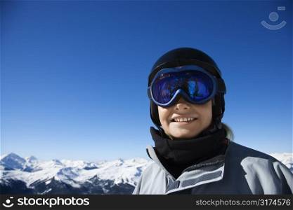 Caucasian teenage boy snowboarder wearing helmet and goggles on mountain looking at viewer.