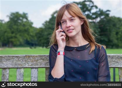 Caucasian teenage girl with red hair phoning with mobile phone in nature