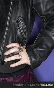 Caucasian woman&acute;s hand on hip wearing silver rings and black leather jacket.