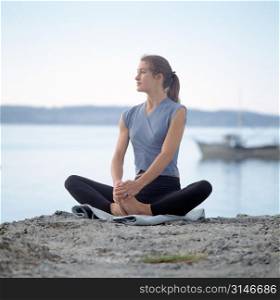 Caucasian Woman Doing Yoga On A Rock Overlooking A Lake