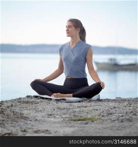 Caucasian Woman Doing Yoga On A Rock Overlooking A Lake