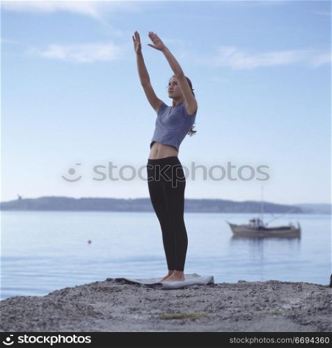 Caucasian Woman Doing Yoga On Lake Shore