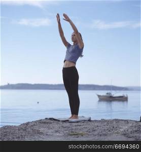 Caucasian Woman Doing Yoga On Lake Shore