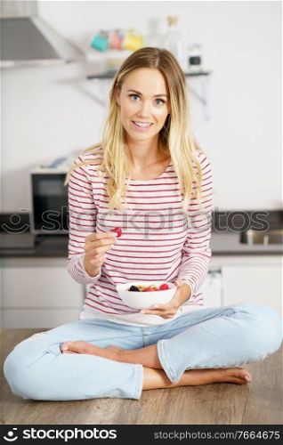 Caucasian woman eating an appetizer with nuts, raspberries and blackberries. Concept of healthy diet.. Caucasian woman eating an appetizer with nuts, raspberries and blackberries.