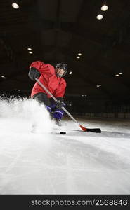 Caucasian woman hockey player sliding kicking up ice.