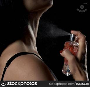 caucasian woman holds a glass transparent bottle with perfume in her hand and presses the spray, close up