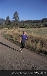 Caucasian Woman Jogging Along A Mountain Valley Road